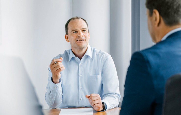 Das Bild zeigt den technischen Geschäftsführer der Amprion GmbH, Herrn Doktor Neumann. Herr Doktor Neumann befindet sich in einem Büro in einer Interview-Situation. Herr Doktor Neumann trägt ein hellblaues Hemd ohne Sakko.