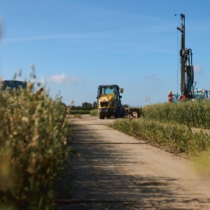 Ein Bagger und ein Bohrer am Ende einer Baustraße auf einem Feld.