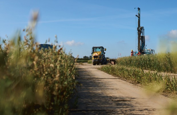 Ein Bagger und ein Bohrer am Ende einer Baustraße auf einem Feld.