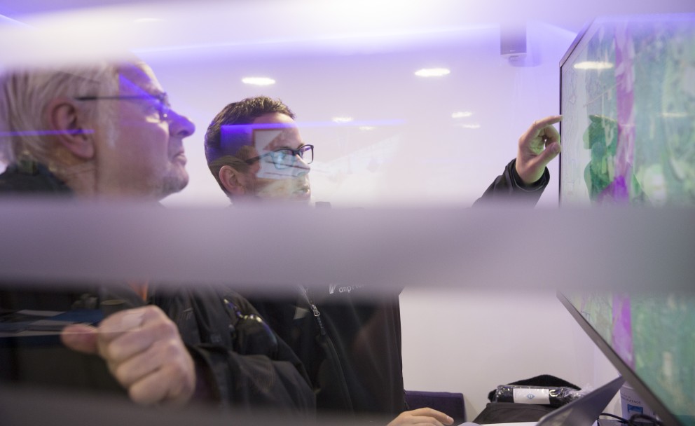 Zwei Männer betrachten gemeinsam einen Bildschirm mit einer digitalen Karte.
