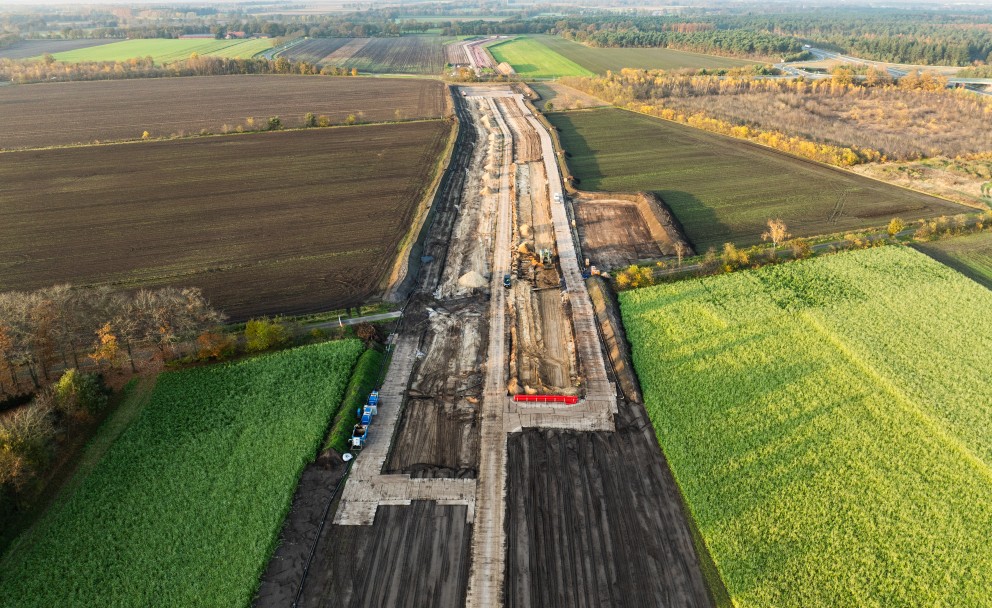Luftaufnahme einer Baustelle für eine Straße oder Bahntrasse zwischen landwirtschaftlichen Feldern