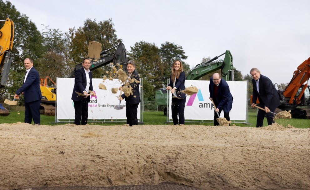 Die abgebildete Szene zeigt den symbolischen ersten Spatenstich für die Erdkabel-Stromtrasse A-Nord in Rhede (Ems) im Oktober 2023. Bei dieser Veranstaltung, die den Baubeginn markierte, waren mehrere prominente Persönlichkeiten anwesend: 
Olaf Lies: Der damalige niedersächsische Umwelt- und Energieminister und heutige Ministerpräsident Niedersachsens (dritter von links) nahm an der Zeremonie teil.
Robert Habeck: Der Bundesminister für Wirtschaft und Klimaschutz (zweiter von rechts) war ebenfalls vor Ort.
Weitere Teilnehmer: Zu den weiteren Personen gehörten Vertreter des Übertragungsnetzbetreibers Amprion (deren Logo auf den Schildern zu sehen ist), darunter die technische Geschäftsführerin Dr. Alexandra Gropp (dritte von rechts), und der nordrhein-westfälische Ministerpräsident Hendrik Wüst (links). 