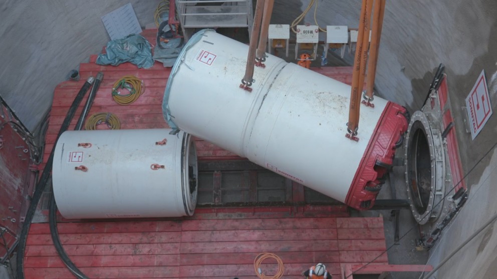 Das Bild zeigt eine rot/weiße Tunnelbohrmaschine in einem Betonschacht.