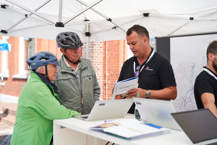 Projektsprecher Florian Zettek zeigt zwei Interessierten die Projektbroschüre von Korridor  B