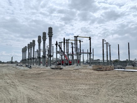 Freiluft-Umspannwerk mit mehreren hohen Isolatoren und Stahlkonstruktionen unter bewölktem Himmel