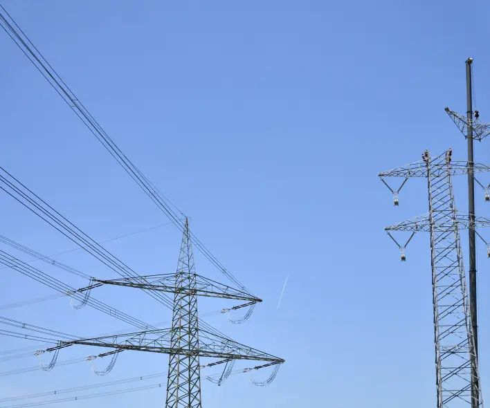 Monteure arbeiten gesichert am neuen Mast.