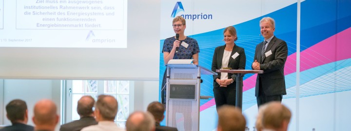 Das Bild zeigt das Podium des Kundentages. Auf dem Podium stehen zwei Frauen und ein Mann.