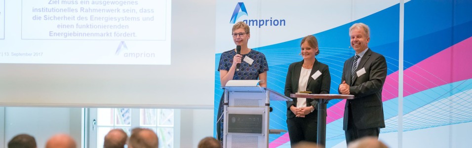 Das Bild zeigt das Podium des Kundentages. Auf dem Podium stehen zwei Frauen und ein Mann.