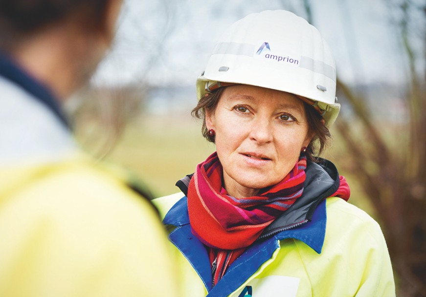 Nahaufnahme einer Frau mit gelber Schutzjacke und weißem Helm.