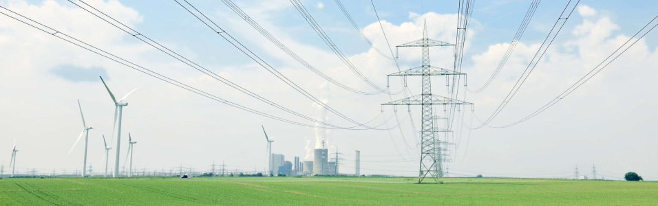 Das Bild zeigt eine Stromtrasse und Windräder in einem grünen Feld - im Hintergrund ein Kraftwerk