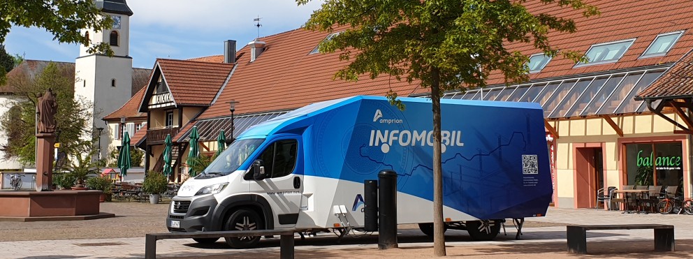 Das Bild zeigt das blau/weiße Infomobil auf einem Marktplatz.