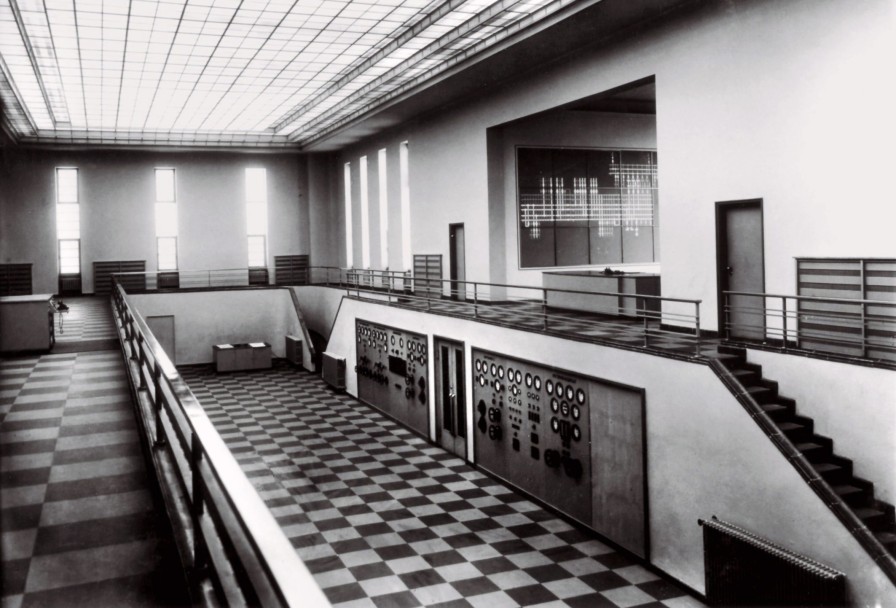 Das Foto zeigt eine schwarz/weiß-Aufnahme des Innebereiches der Hauptschaltleitung in Brauweiler: Gefließter Raum, große Analoganzeigen.