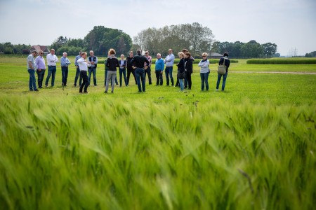 Das Bild zeig eine Gruppe Menschen auf einem grünen Acker.