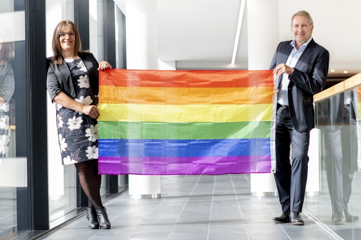 Foto von Nina Meyer und Dr. Brick. Sie halten einen Regenbogenflagge.