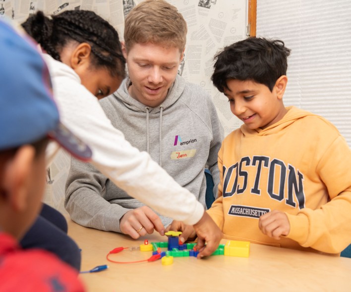 Mehrere Kinder sitzen an einem Tisch und bauen mit bunten Steckbausteinen ein Modell