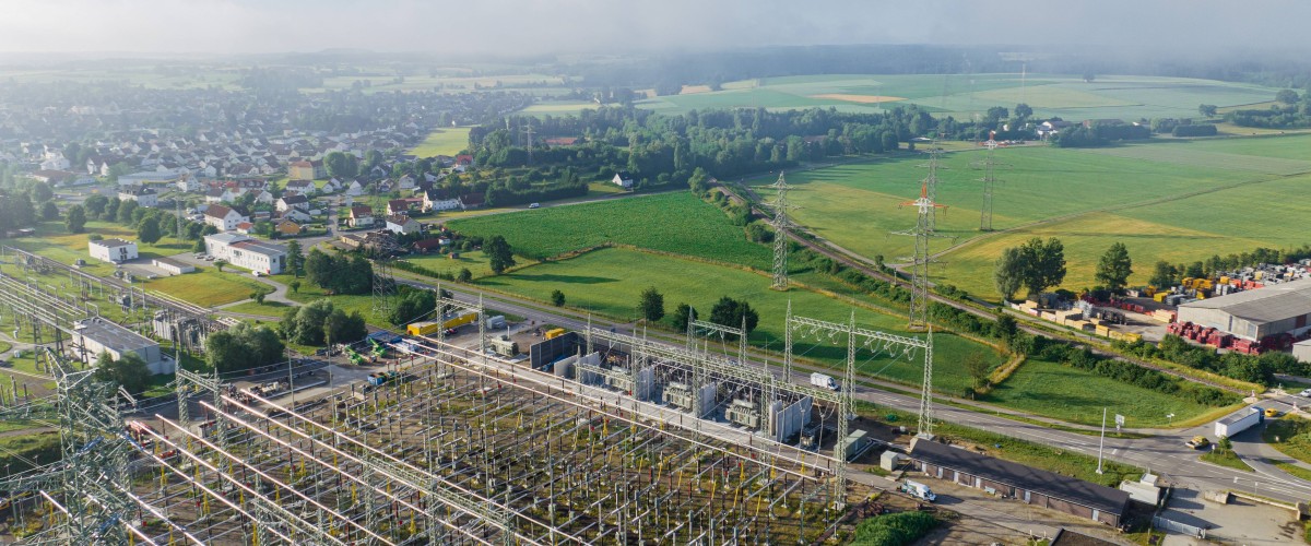 Luftaufnahme mit Blick auf die Umspannanlage Hebertingen von Amprion bei leicht bewölktem blauen Himmel und grünen Feldern im Hintergrund