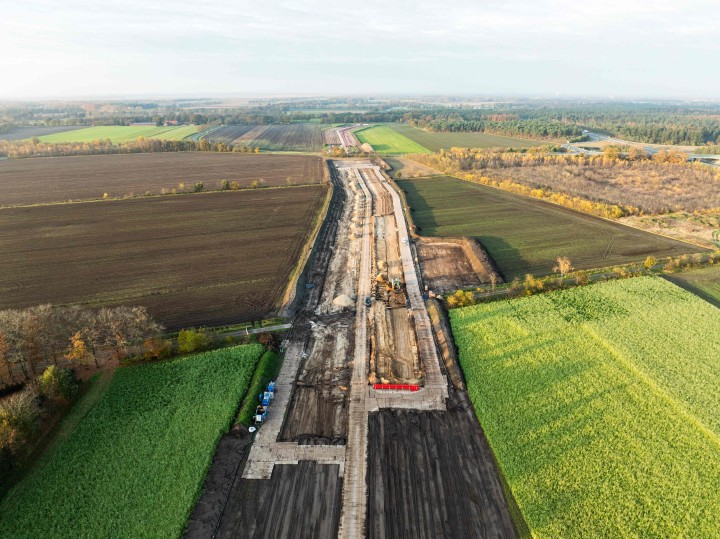 Luftaufnahme einer Baustelle für eine Erdkabel-Trasse, die sich als breiter, dunkler Erdstreifen durch eine Landschaft aus grünen und braunen Feldern zieht.