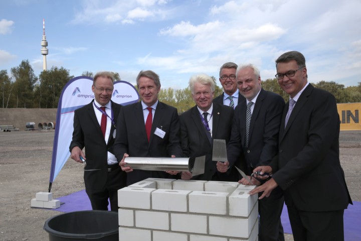 Menschen vor einem gemauerten Kasten. Herr. Dr. Brick trägt eine Kapsel aus Metall.