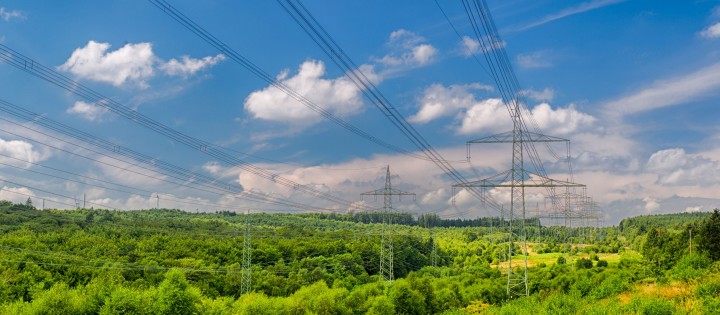 Das Bild zeigt eine Trasse in hügeliger Landschaft und baluem Himmel.