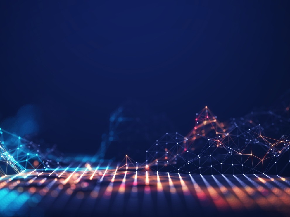 Das Bild zeigt eine abstrakte, digitale Landschaft, die eine Datenverbindung oder ein Netzwerk darstellt. Der Hintergrund ist ein dunkles, tiefes Blau. Im unteren Bereich des Bildes erstreckt sich eine Gitterstruktur aus leuchtenden Punkten, die durch Linien miteinander verbunden sind. Diese Struktur erstreckt sich perspektivisch nach hinten. Die Punkte und Linien sind von links in kühlem Blau und Türkis, in der Mitte in warmen Orange- und Rosatönen und nach rechts in weiteren warmen Farbtönen beleuchtet. Einzelne hellere Punkte schweben in der Luft.