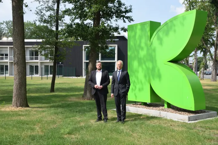 „Klaus Wewering (links), Leiter Großprojekte bei Amprion, und Moritz Böcking (rechts), Geschäftsführer von Klasmann-Deilmann, stehen vor einem großen, grünen Firmenlogo in Blattform und dem neuen Innovationszentrum des Unternehmens.“ 