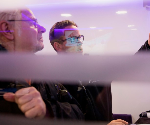 Das leicht lilafarbene Bild zeigt einen Amprion-Mitarbeiter, der einem Bürger an einem Bildschirm die Trassenkorridore im Projekt A-Nord erläutert.