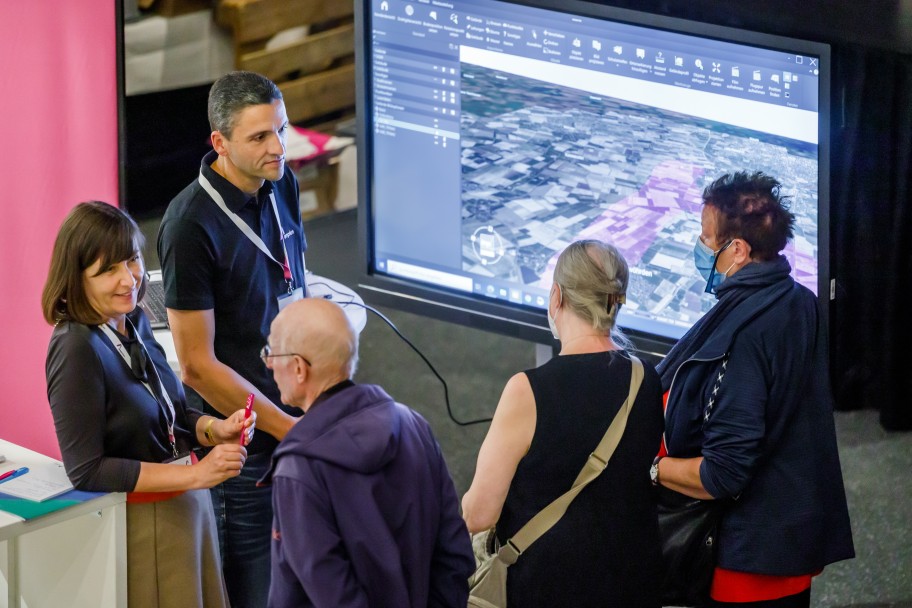 Gesprächsrunde vor einem großen Bildschirm beim Bürgerinfomarkt in Heide