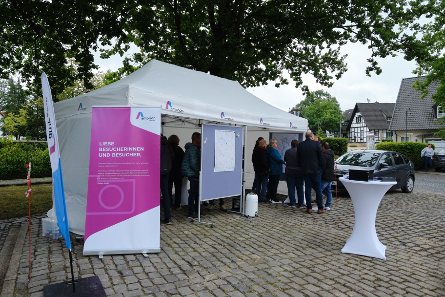Pavillonzelt auf einem gepflasterten Okatz unter einem Baum mit rund zehn Personen