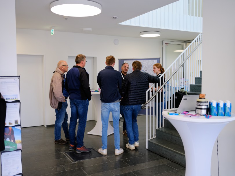 Gesprächsrunde zwischen sechs Person, der Großteil steht mit dem Rücken zur Kamera