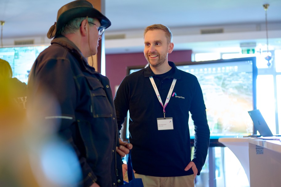 (c) Tennet/Timo Wilke
Zwei dunkel gekleidete Personen stehen nebeneinander, die auf der rechten Seite stehende Person schaut die andere freundlich an.