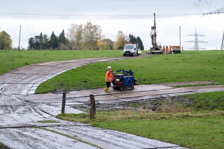 Metallplatten auf einer grünen wiese augelegt, kleines Gerät mit Mensch im Vordergrund, großes Gerät im Hintergrund