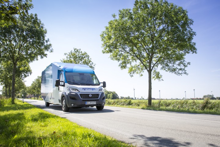 Das Infomobil von Amprion auf der Straße zwischen vereinzelten Bäumen