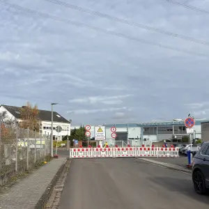 Eine Straße ist mit Absperrbaken und Baustellenhinweisen für Leitungsarbeiten gesperrt; Schilder informieren über Durchgangsverbot.