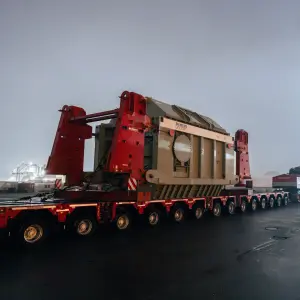 Ein Schwerlasttransport bringt einen großen Siemens-Energy-Transformator bei Nacht auf einem Hafengelände ans Ziel.